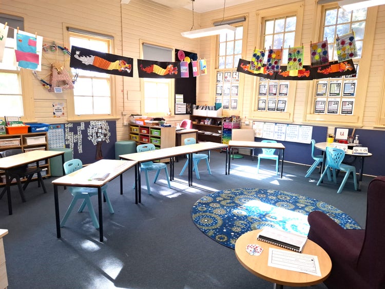 image shows a bright and colourful classroom with artwork displayed around the room