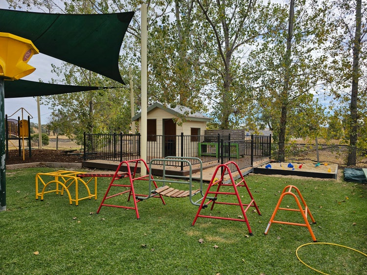 the cubby house is in the centre of the picture. The climbing equipment is in front of the sand pit