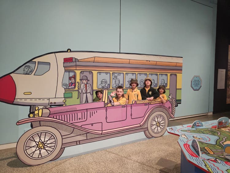 image of 5 students sitting in a pink old fashioned vehicle