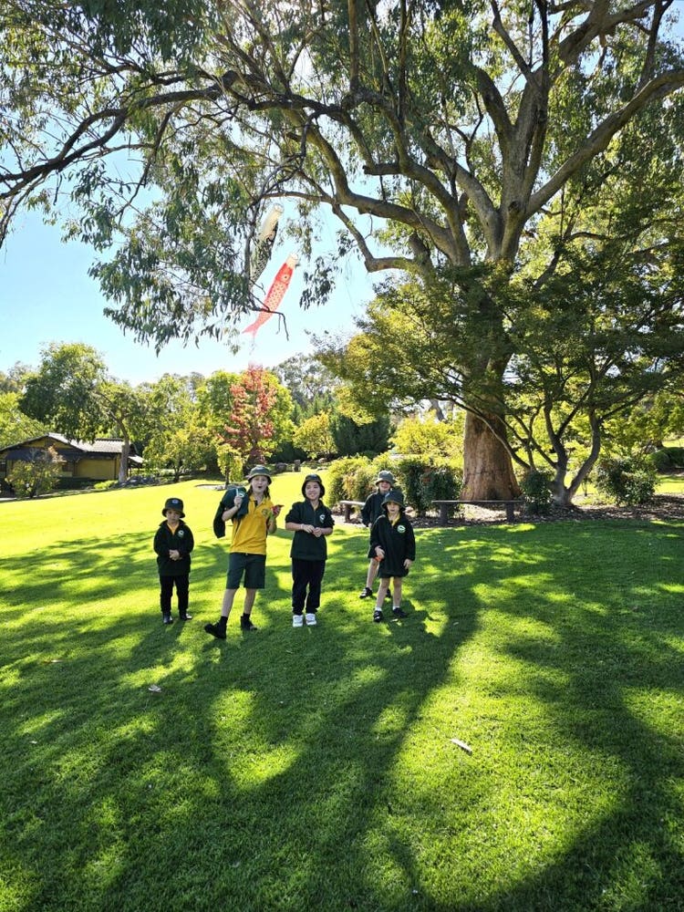 group photo of the students at the local Japanese Gardens. standing on green grass, looking at the camera