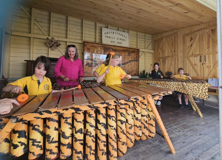 students enjoying a music lesson with their teacher. They are learning to play the marimbas.